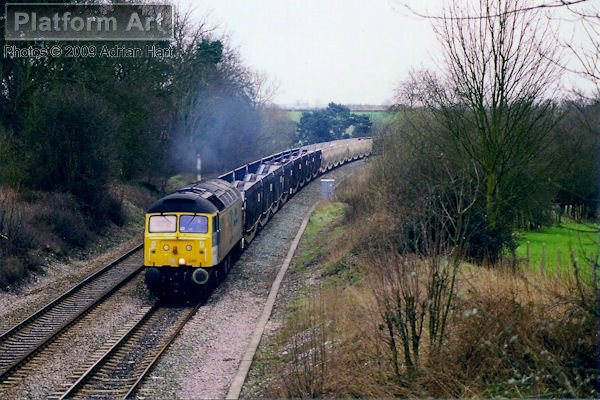 Speedlink liveried Class 47 47245 The Institute of Export approaches Kings Sutton on 24th February 1998 with a northbound service of empty cartics.
